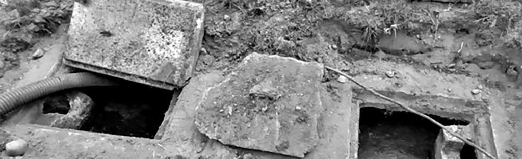 Broken concrete septic tank covers with branches and drain and dirt