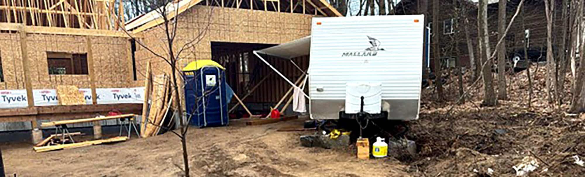 Construction site with house framing and trailer in wooded area