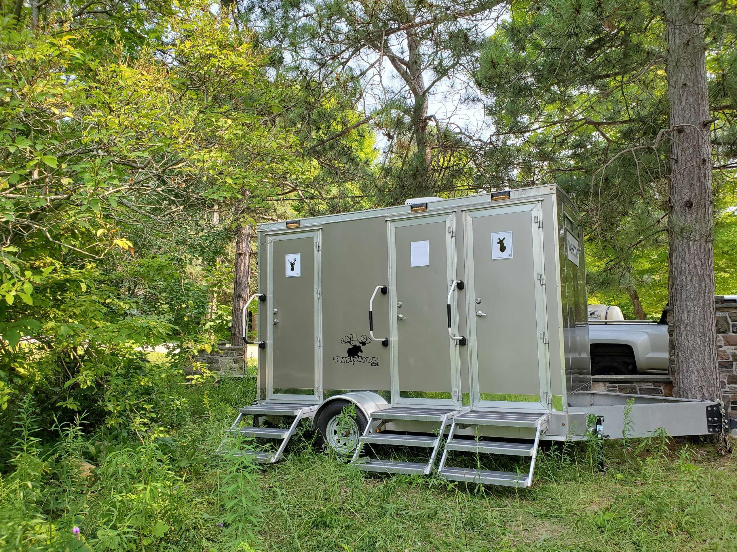 Portable restroom trailer in forest setting with nature backdrop