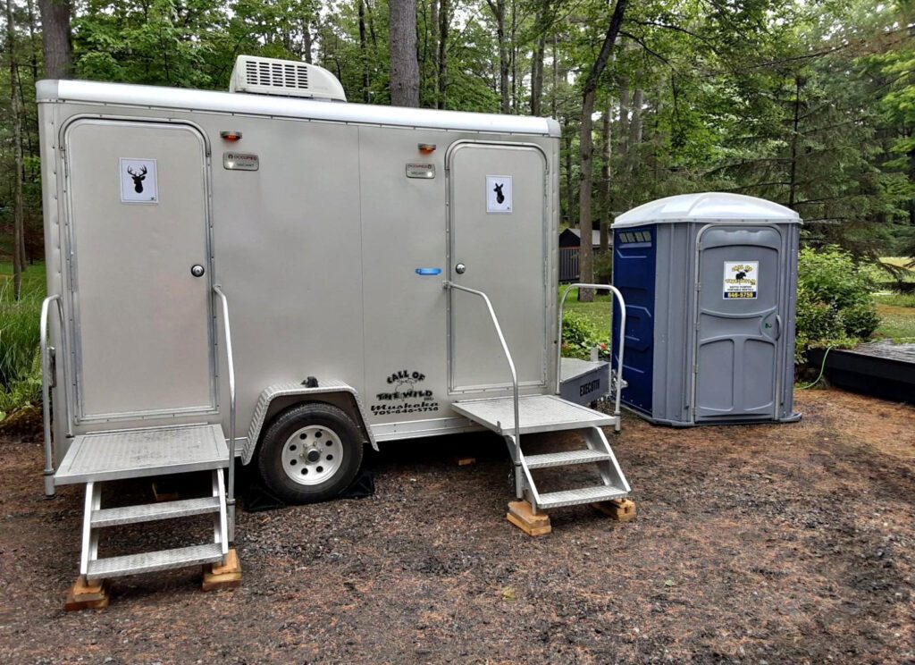 Portable restroom trailer and portable toilet in wooded area for outdoor events