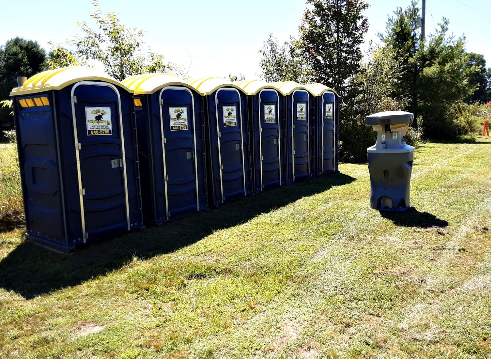 Outdoor portable toilets and handwashing station on grassy field
