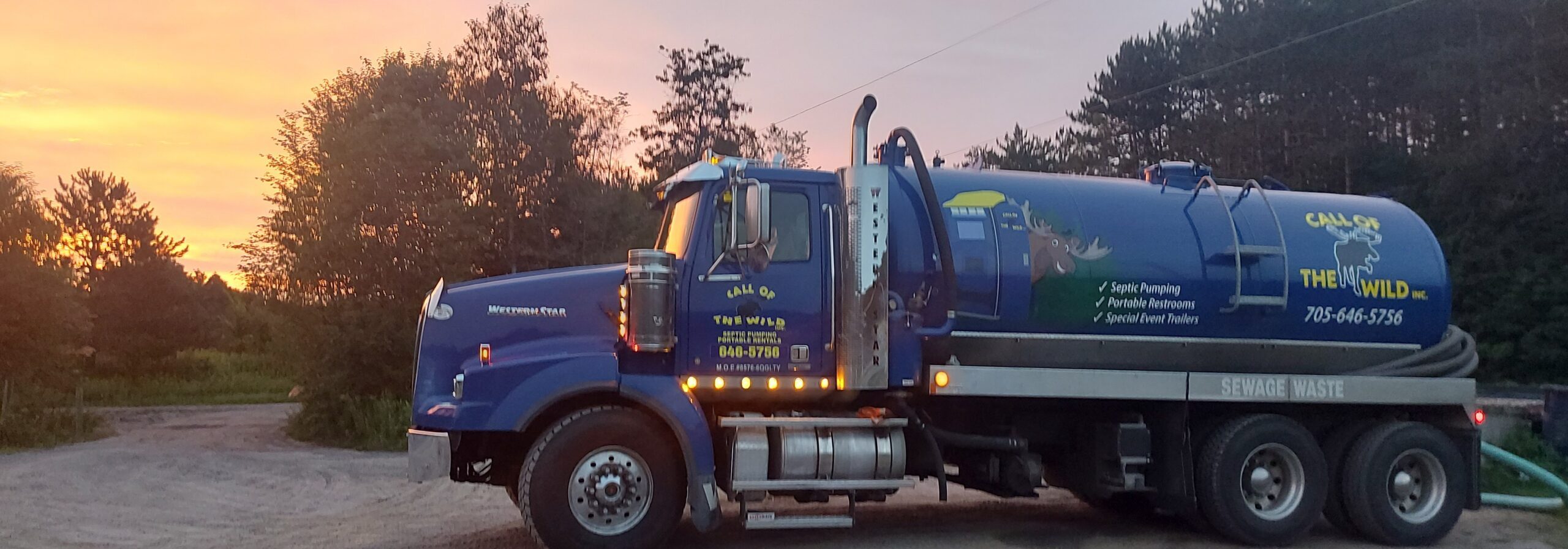 Septic pumping truck at sunset near forest and residential area