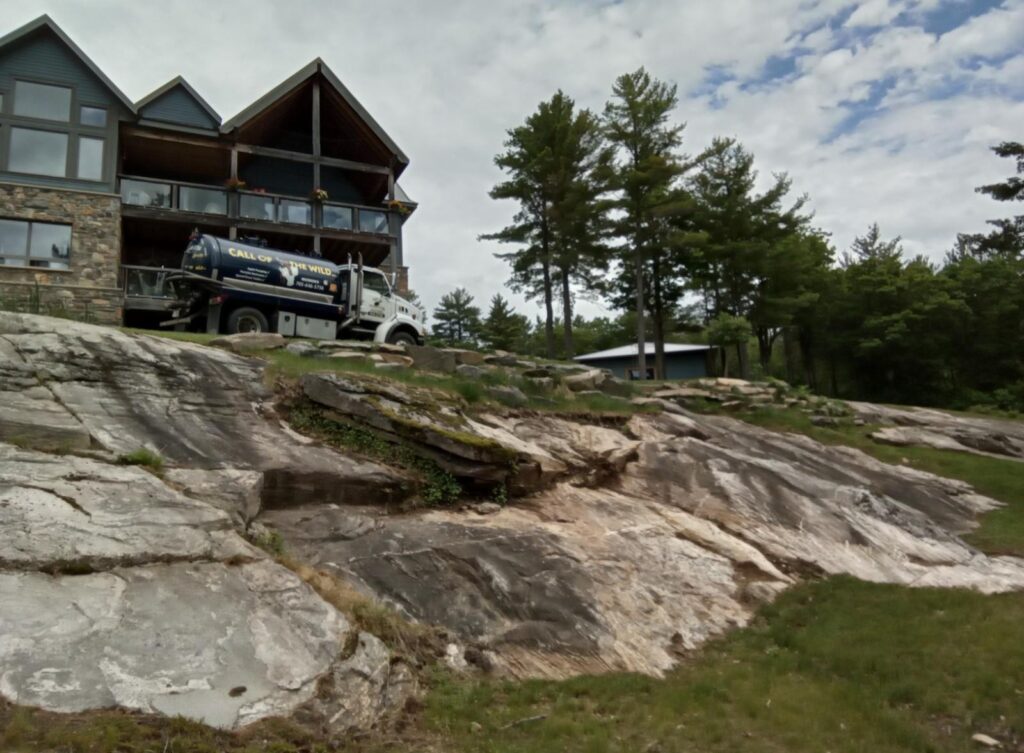 Septic truck servicing rural property in wooded area