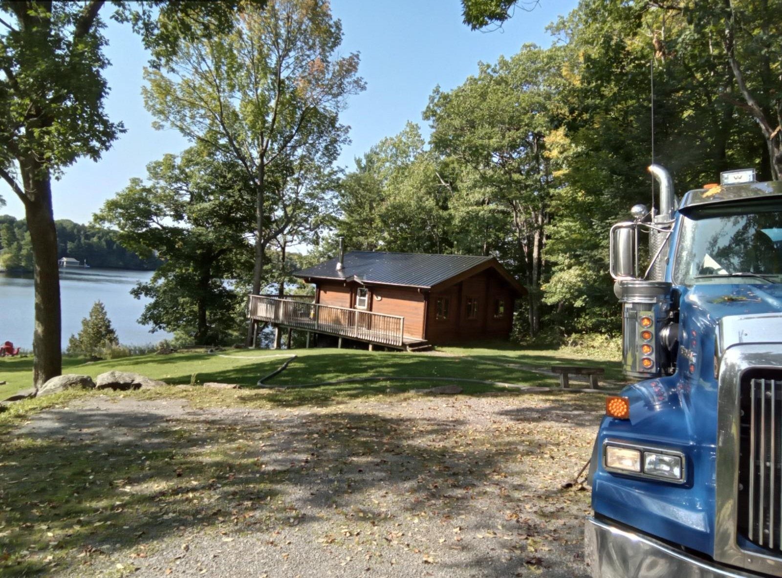 Cabin by a lake with a blue truck in the foreground