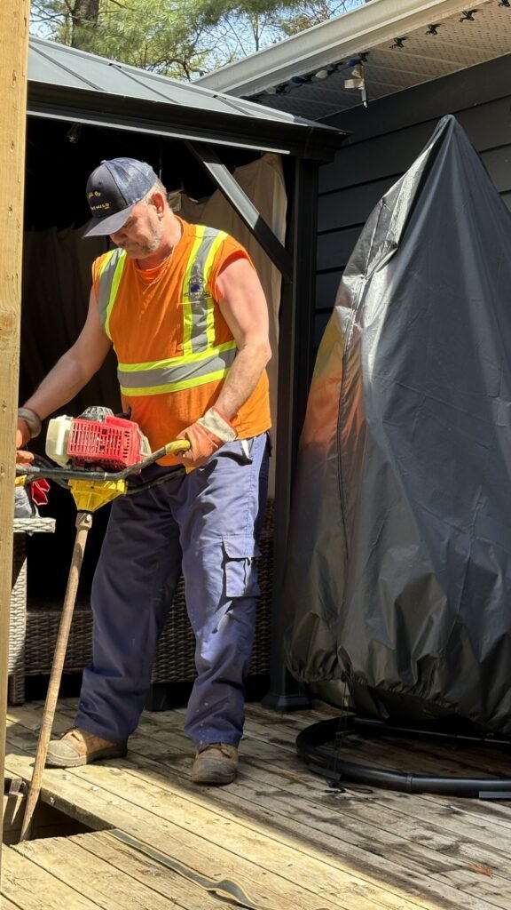 Construction worker using equipment on a wooden deck in bright sunlight