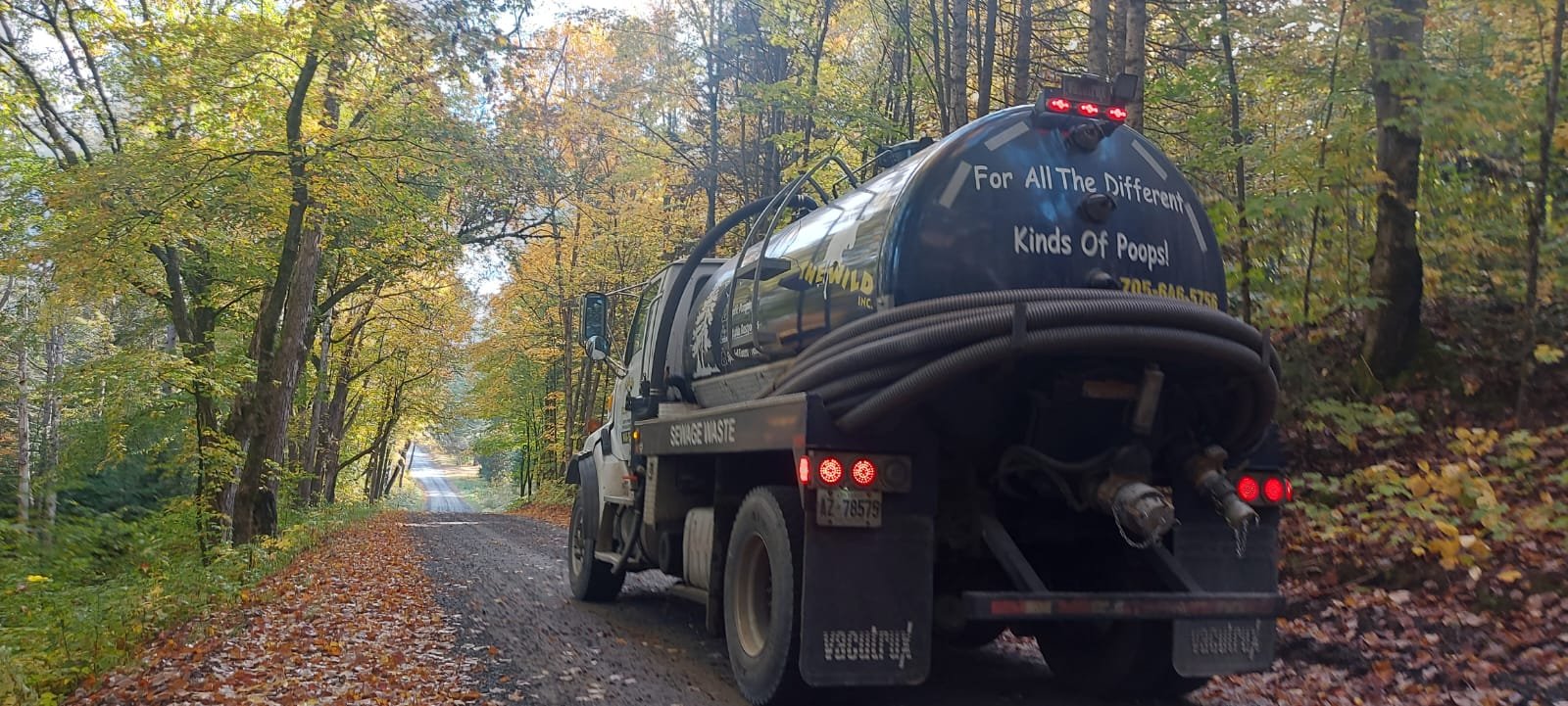 Septic tank truck on forest road during autumn, servicing various properties