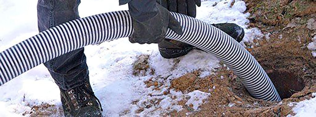Technician drains septic system in snowy yard