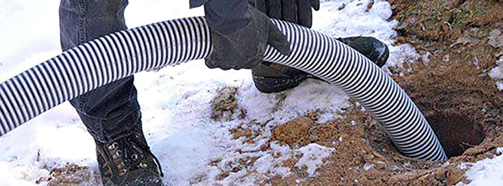 Technician drains septic system in snowy yard