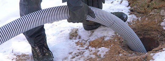 Technician installing flexible drainage pipe in snowy ground