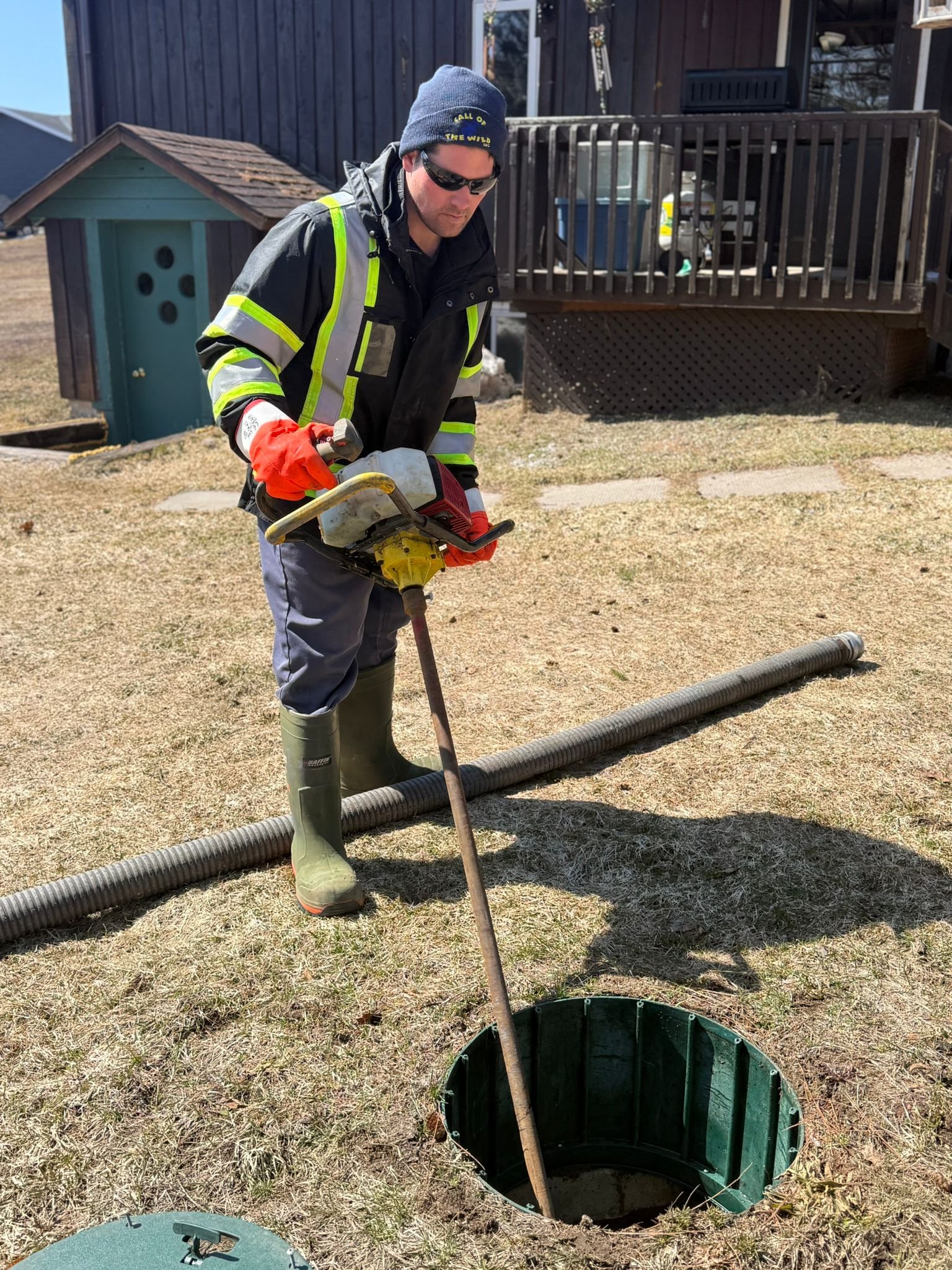 Worker maintaining rural septic tank with safety gear