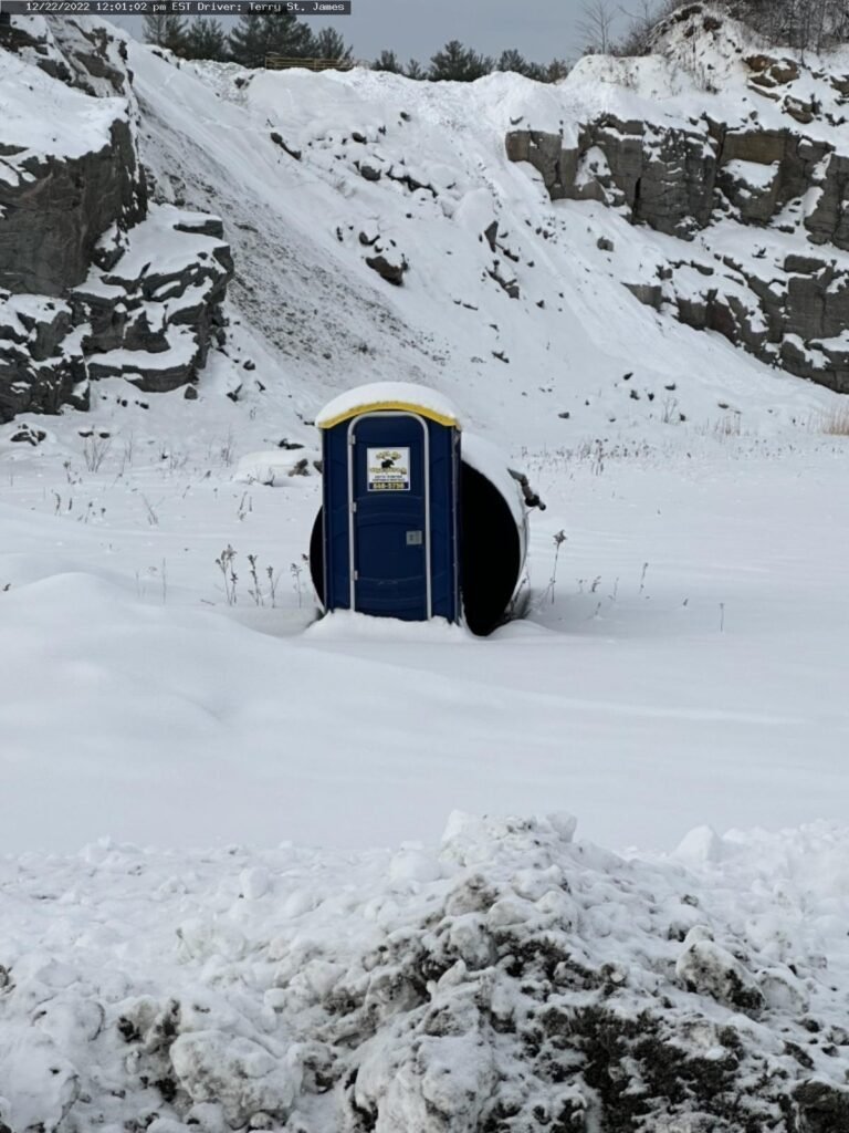 Lone portable toilet in snowy quarry landscape
