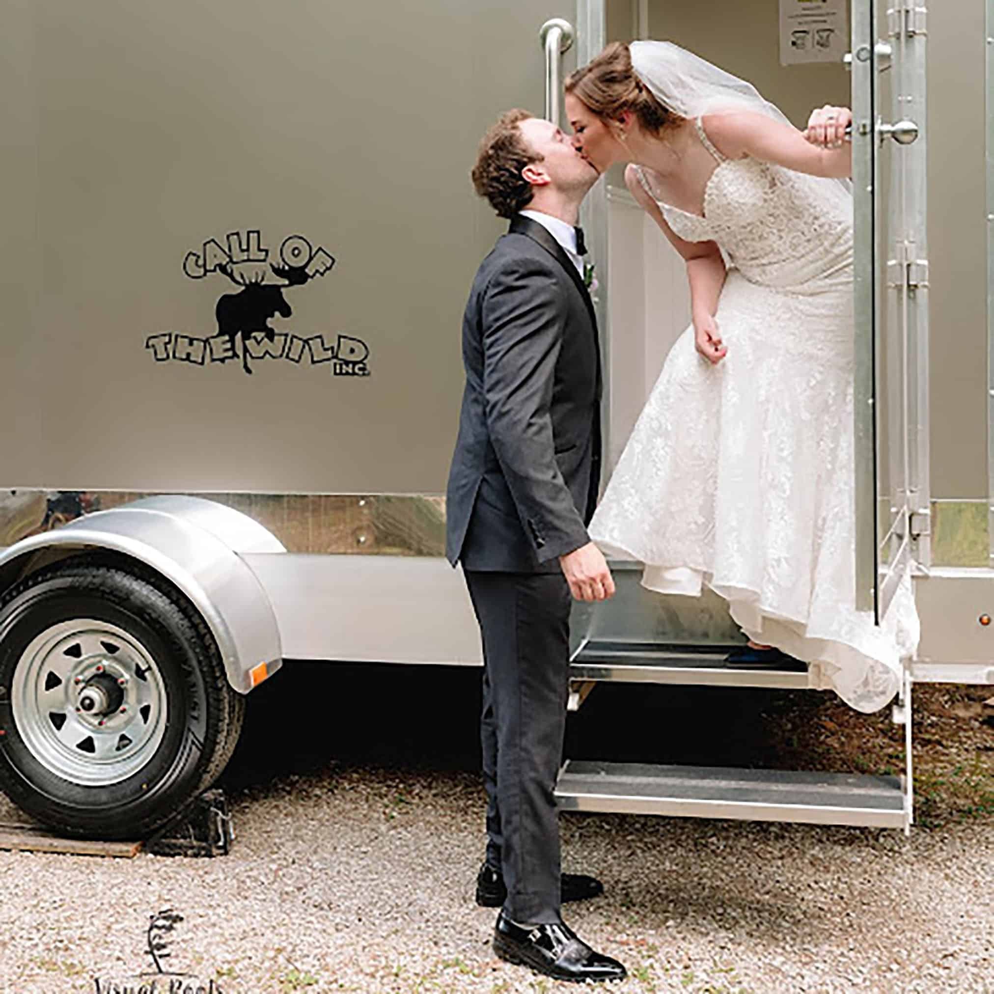 Bride and groom kissing outside mobile restroom trailer by Call of the Wild